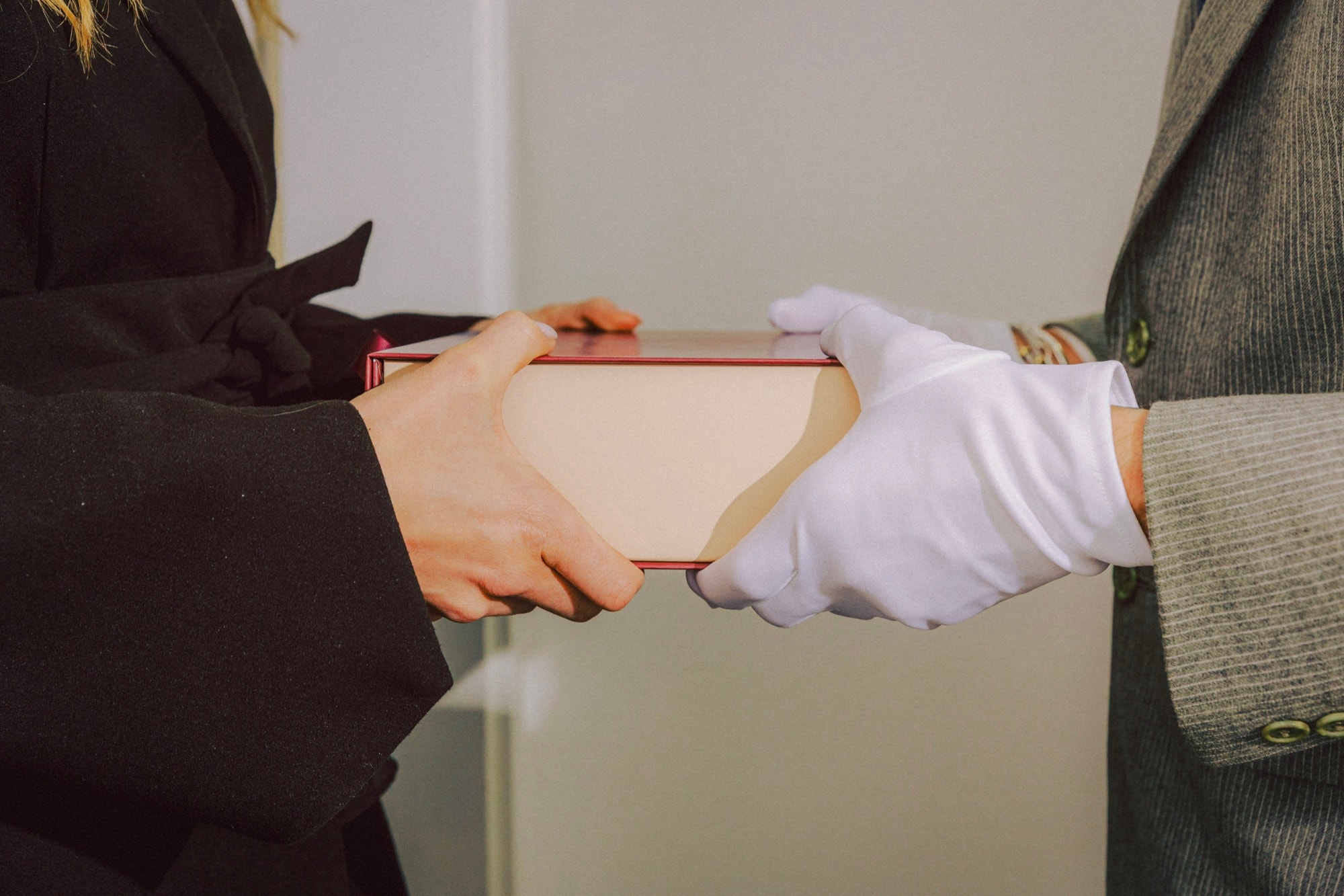 A Ring & Robe cookie box passed from hand to white-gloved hand